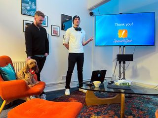 Photograph of two representative of SpecialEffect at the Third Kind Games offices standing in front of a presentation with the words 'Thank you' displayed, along with the SpecialEffect logo.