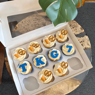 Cupcakes with decorations that spell out 'TKG 7' and have beer and pretzels on the top of them.